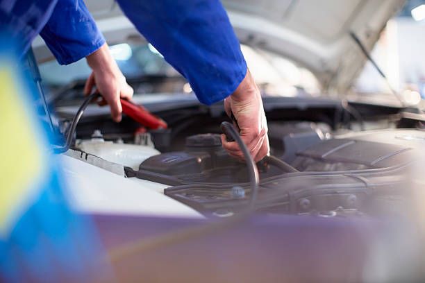Technician performing car battery test under the hood at Tuttle-Click Tustin Chrysler Jeep Dodge Ram in Tustin, CA