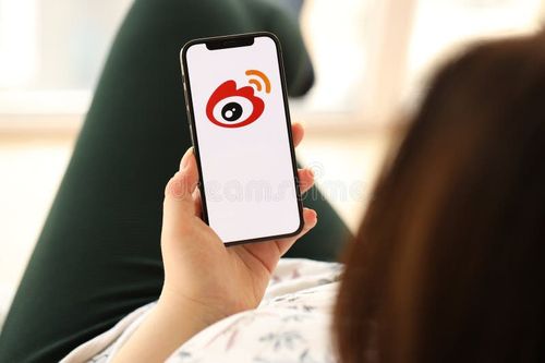 KYIV, UKRAINE - APRIL 1, 2024 Sina Weibo icon on smartphone screen in young female hands. Indoors. Woman using iPhone app at home. Weibo app stock images, royalty-free photos and pictures