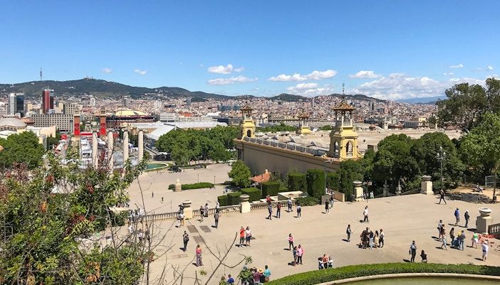 Cable car ascending Parc de Montjuic, Barcelona, with cityscape and Mediterranean Sea in the background.
