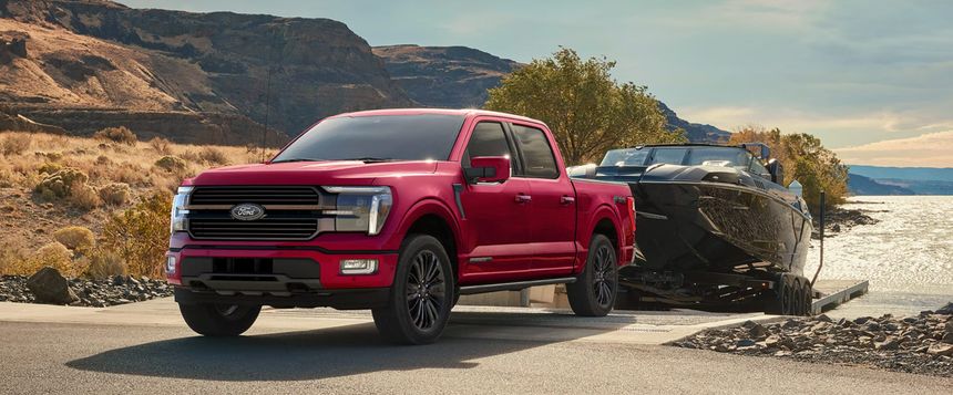 Red Ford F-150 towing a boat near the water available at Irvine Ford in Irvine CA