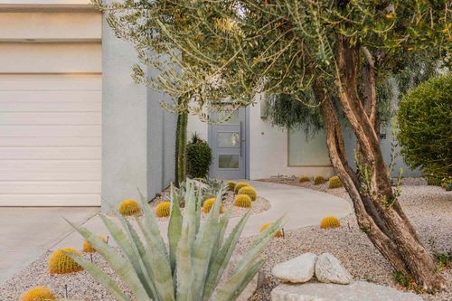 Concrete paved to front entrance of modern home with desert plants in front