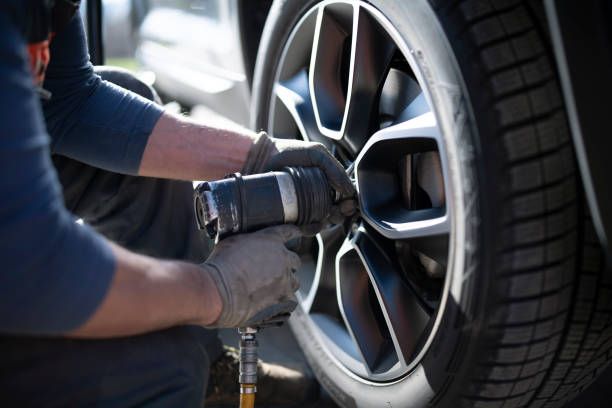 Automotive technician tightening wheel lug nuts during routine maintenance service at Tuttle-Click Tustin Chrysler Jeep Dodge Ram in Tustin, CA