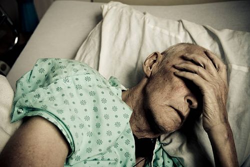 sick and senior man wearing hospitable gown lying in bed - sick elderly stock pictures, royalty-free photos & images