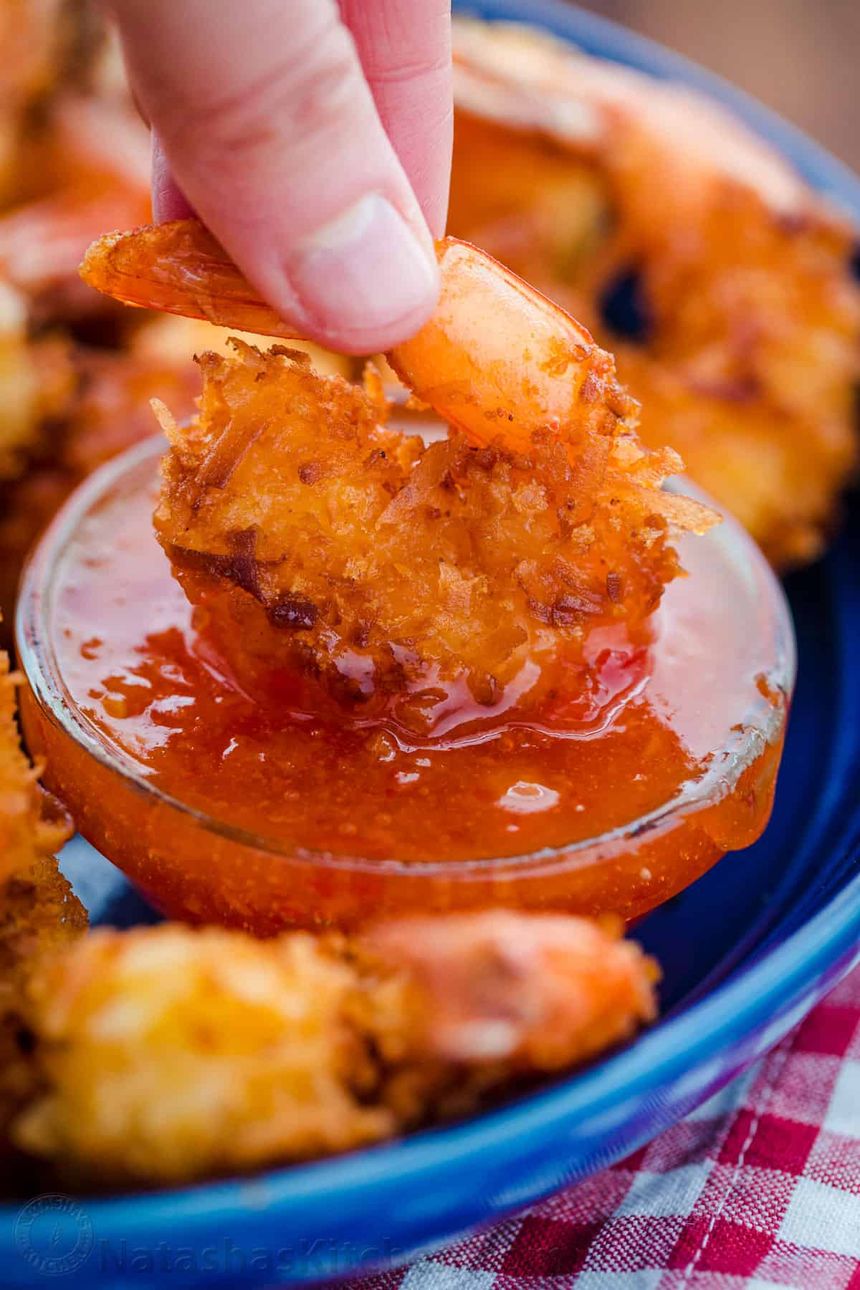 Up close coconut shrimp dipping into coconut shrimp sauce