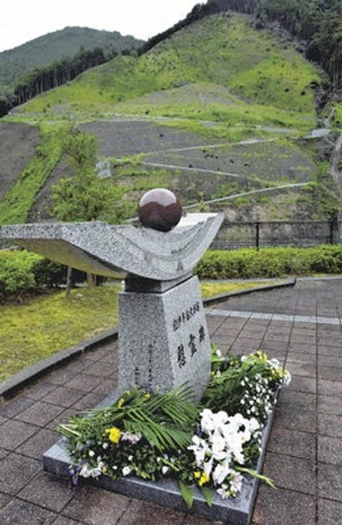 式典後、崩れた跡を望む慰霊碑に花が手向けられた（五條市大塔町で）