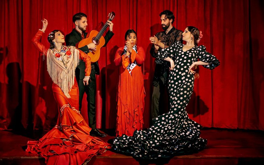 Flamenco dancers in traditional attire performing on stage at Laietana, Barcelona.