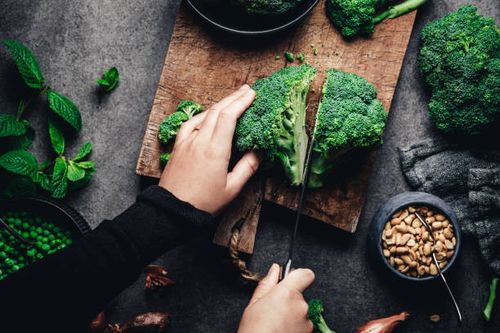 woman cutting fresh broccoli - broccoli stock pictures, royalty-free photos & images