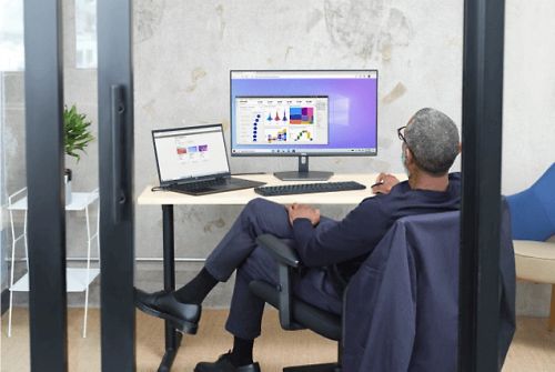 一个人在办公室的桌旁工作，一台笔记本电脑连接到到一个桌面显示器