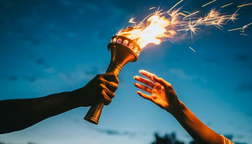 Dynamic flaming torch handover symbolizing leadership legacy and shared responsibility at dusk