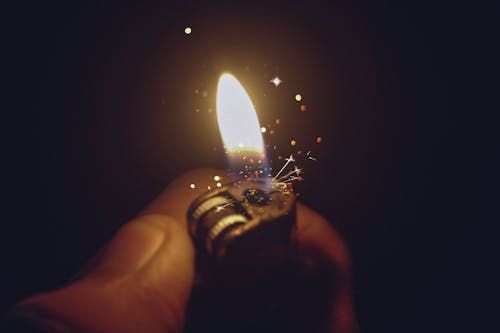 Free Intense close-up of a lighter igniting a bright flame with spark effects against a dark background. Stock Photo