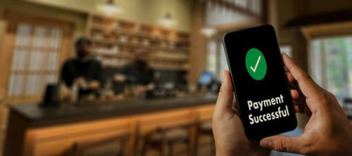 Customer using a smartphone online money transfer confirmed at the cafe coffee technology lifestyle payment screen a banking payment on a mobile phone Stock Photo