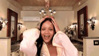 a woman in a pink robe is holding her hair and smiling