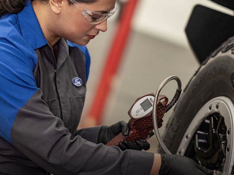 Ford service technician checking tire pressure during maintenance at Irvine Ford service center