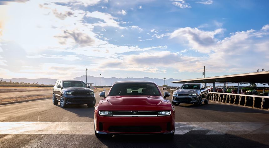 Front view of Chrysler, Dodge, and Jeep vehicles lined up outdoors under a blue sky, showcasing performance and design.
