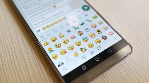 Imagem de um celular com a aba de emojis aberta no WhatsApp