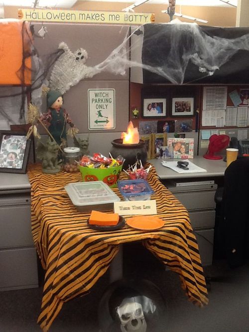 an office cubicle decorated for halloween with decorations on the desk and pictures hanging from the ceiling