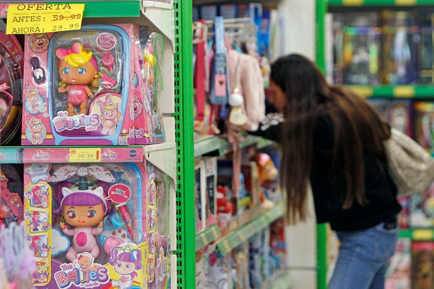 Una mujer busca el juguete en el lineal de un supermercado.