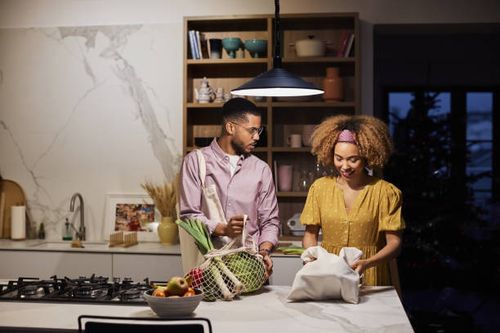 man looking at afro girlfriend with groceries - night kitchen stock pictures, royalty-free photos & images