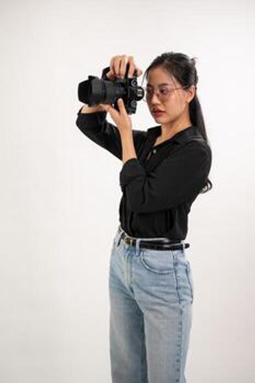 A professional, confident Asian female photographer is taking pictures in a photoshoot studio. photo
