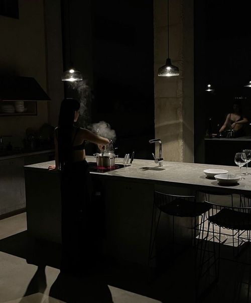 a woman is cooking in the kitchen at night