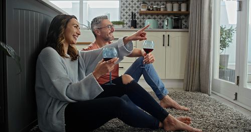 这是一对幸福的夫妇在厨房地板上喝着酒放松的照片图片下载