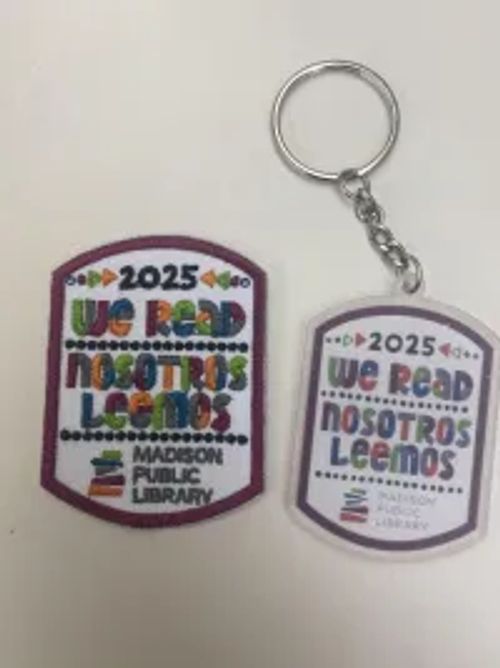 WE READ Nosotros leemos badge and keychain from Madison Public Library.