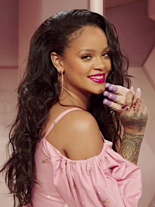 Rihanna smiling, holding three Fenty products