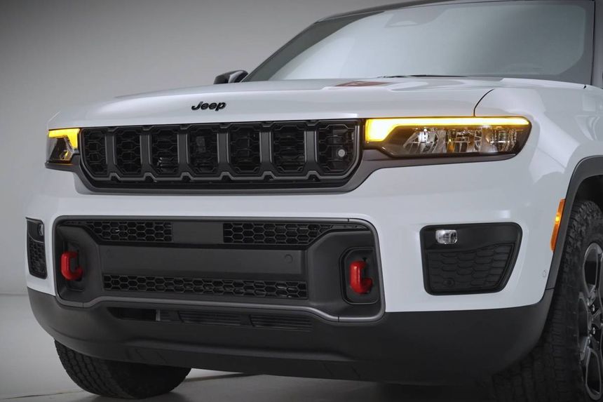 Front grille and LED headlight design of white Jeep SUV showcasing modern exterior styling