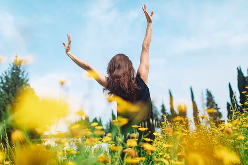 年轻女子在花圃里享受阳光图片下载