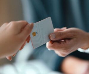 Close-up of two people exchanging a contactless credit card during a payment transaction.