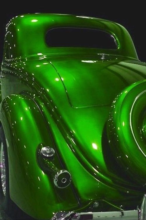 a shiny green car is parked in the dark