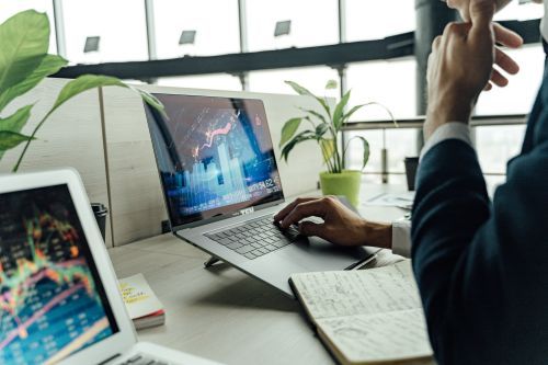 Free A professional analyzing stock market data on a laptop in a bright office environment. Stock Photo