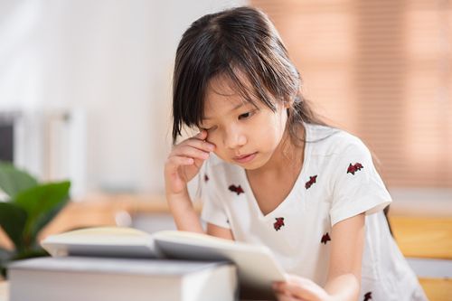 小亚洲学生女孩试着在家里在线学习的同时专注于看书作为一种近视的预防照片下载