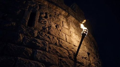 Illuminated Stone Tower A Torch's Glow Against Ancient Walls