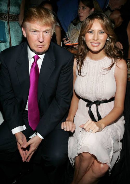 Real estate developer Donald Trump and his wife Melania Trump pose in the front row at the Oscar De La Renta Spring 2006 fashion show during Olympus...