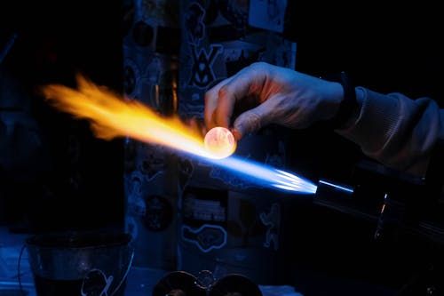 Free Close-up of glass blowing with vivid blue and orange flames indoors. Stock Photo