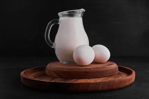 Free Photo eggs and a jar of milk on a wooden board.