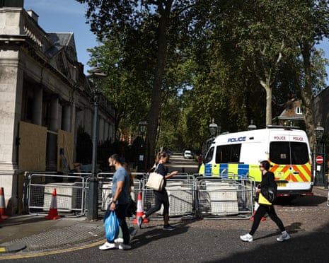 people walking across a street with a police van in the background