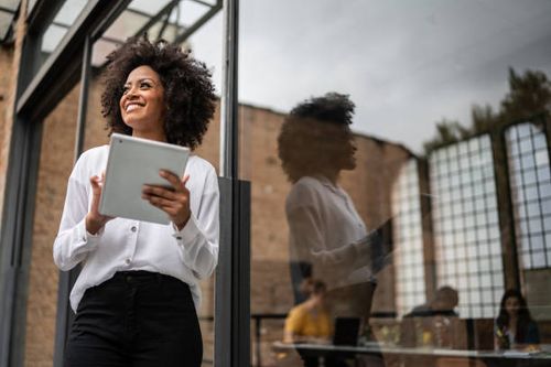 businesswoman looking away and using digital tablet in an office - millennial female professional stock pictures, royalty-free photos & images
