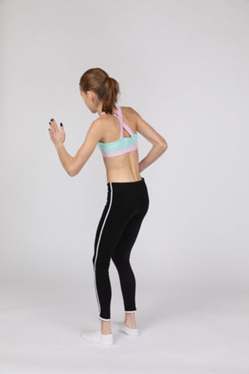 四分之三后视图的运动服向前倾斜，而站在像机器人一样的青少年女孩