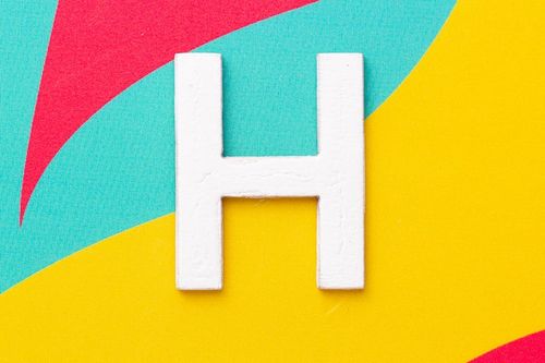 Photo letter h of the alphabet on colored background top view