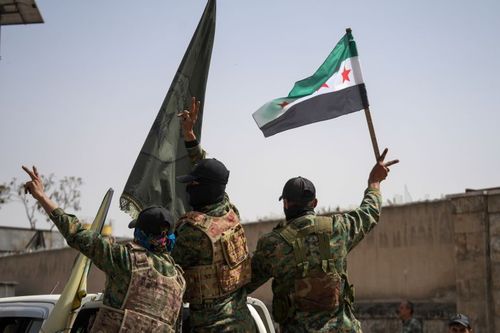 Members of the Syrian Democratic Forces (SDF) flash the victory sign while departing the city of Aleppo, Syria, on April 9, 2025.