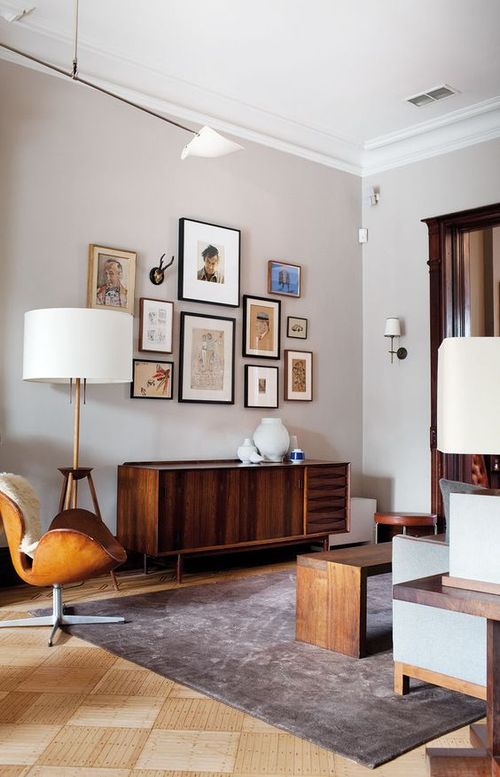 A mid-century modern living room done in neutrals, with stained furniture, a leather chair, a credenza, a gallery wall and table lamps.