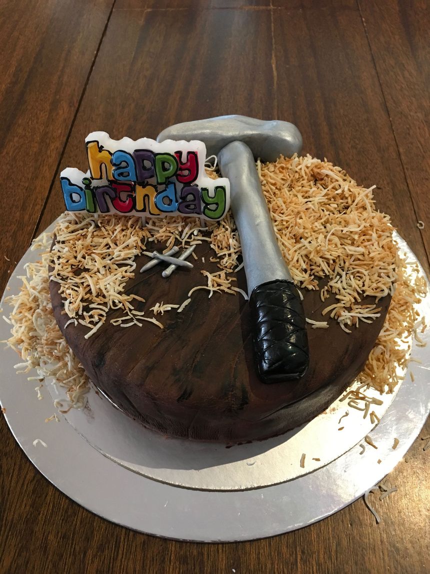 a birthday cake with a hammer and happy birthday sign on it