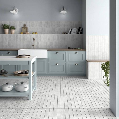 This bright and cheery kitchen features white handmade-look subway tile floor and wall tile and blue cabinets.