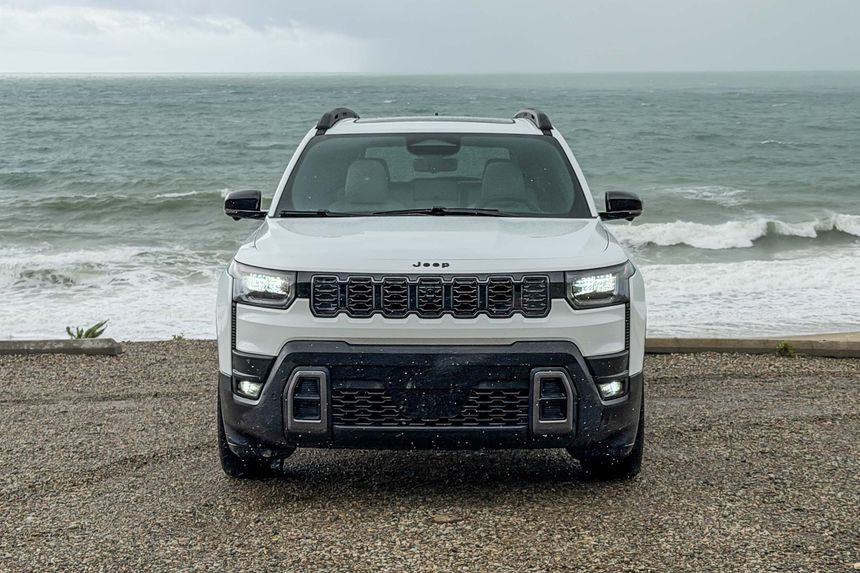 Front view of Jeep SUV parked near ocean coastline showcasing modern design and LED lighting