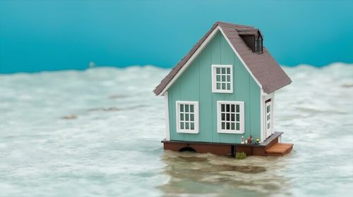 水没するミニチュアハウスモデル。水害のイメージ｜Miniature house model submerged in water. Image of flood damage. Generative AI
