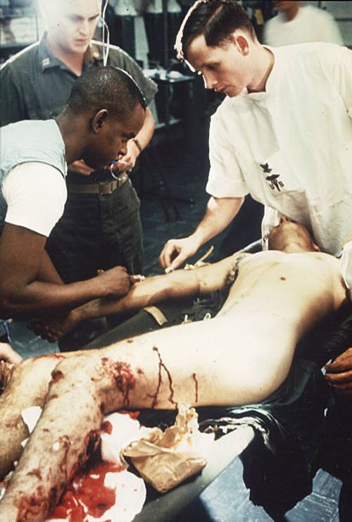 Marine Cpl JA Holland, who sustained heavy shrapnel wounds in his legs, is given treatment in the shock and resuscitation ward of the Amphibious...