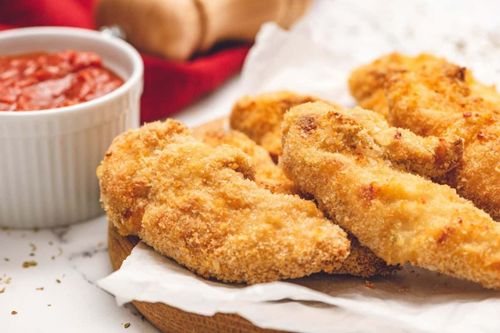 Chicken fingers on platter next to ketchup.