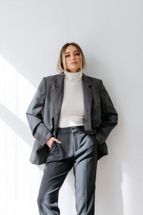 Stylish woman in suit with hands in pockets in studio